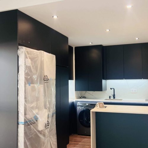 Cocina moderna con muebles azul oscuro y encimera clara en reforma integral de vivienda