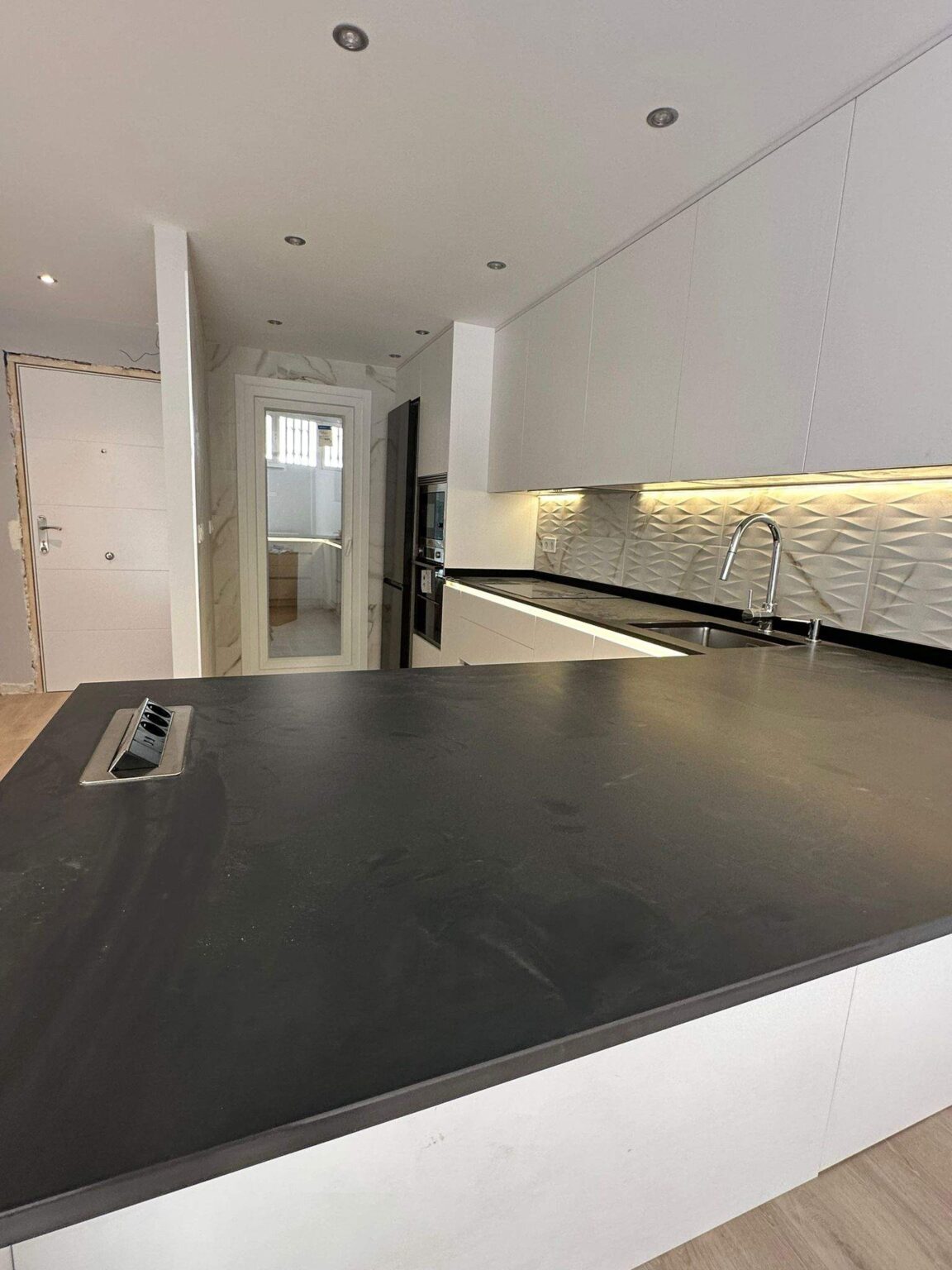 Encimera negra en cocina moderna diseñada en reforma integral de vivienda