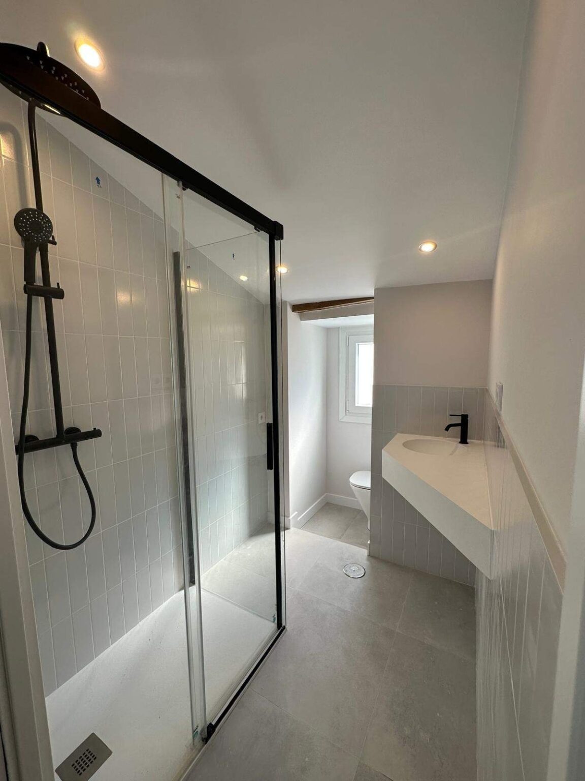 Baño moderno con mampara de cristal y ducha efecto lluvia en proyecto de reforma