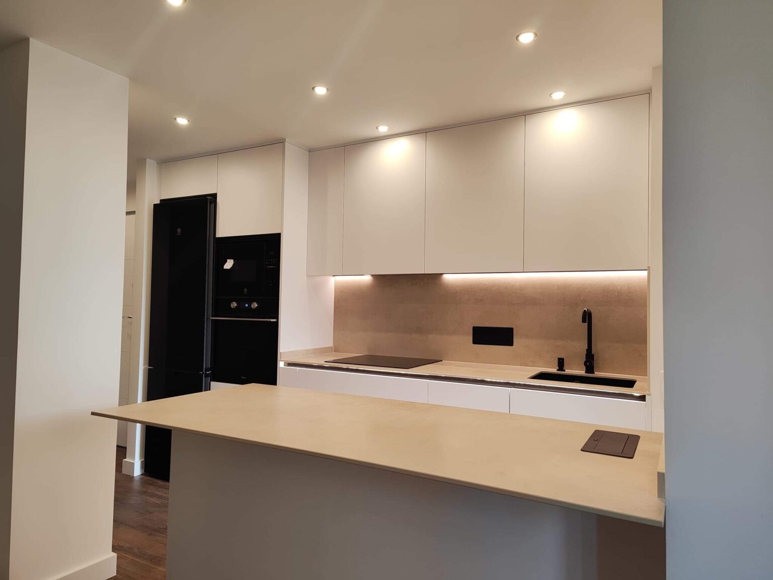 Cocina abierta con iluminación integrada y muebles minimalistas en proyecto de interiorismo